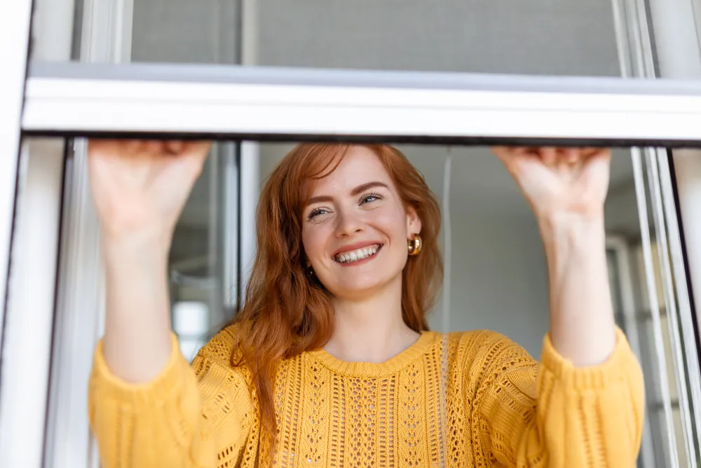 Hand schließt ein Schutzgitter am Fenster